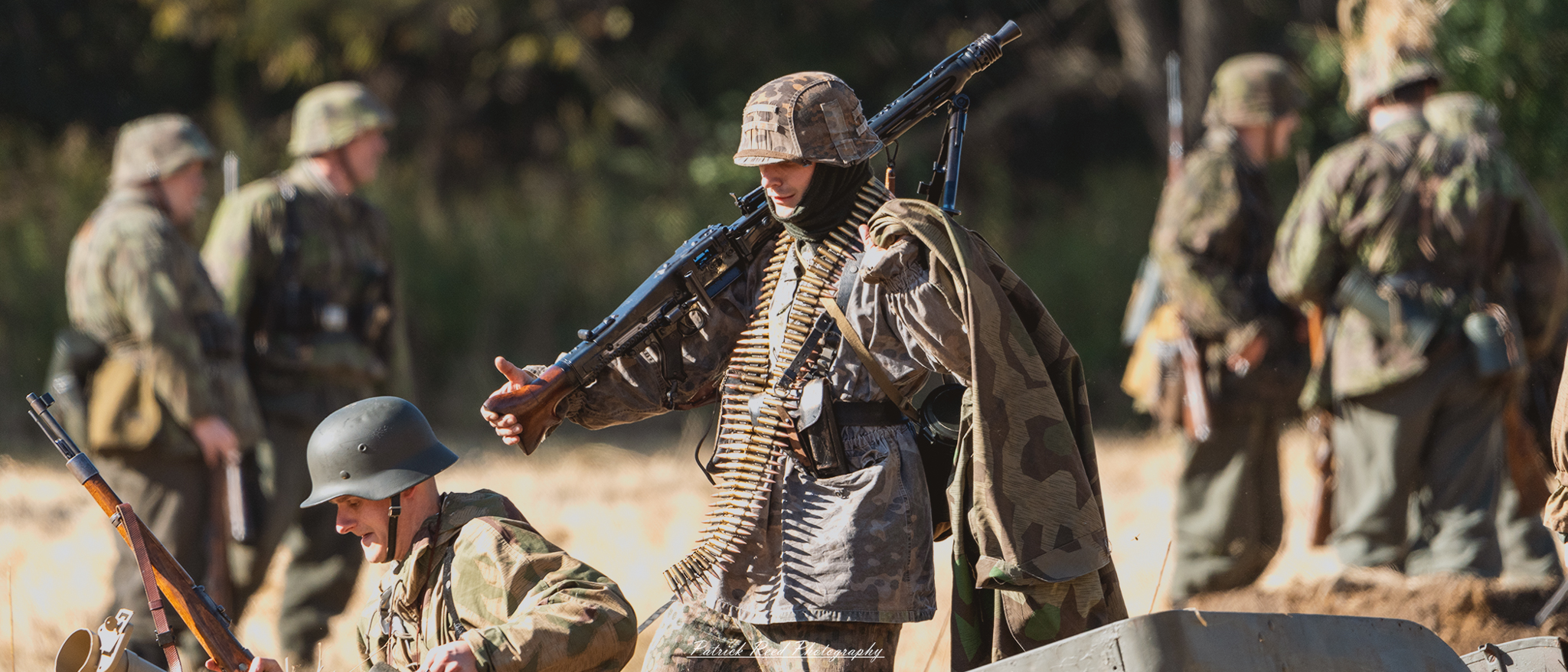 "World War II German machine gunner in a combat setting, dressed in a camouflage uniform with a helmet. He is crouched behind a barricade, focusing intently on his target through the sights of a mounted MG42 machine gun. The background features a war-torn landscape, with debris and smoke, conveying the intensity of battle. The soldier's expression is serious and determined, embodying the resilience and discipline of the German forces during the conflict."